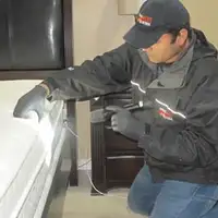 Bed bug inspection technician checking a mattress and bed frame for signs of infestation in Houston, TX
