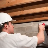 Termite inspection technician checking a basement wall and framing for termite activity in Houston, TX